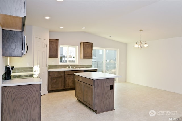 kitchen with light countertops, stainless steel microwave, stove, a kitchen island, and vaulted ceiling