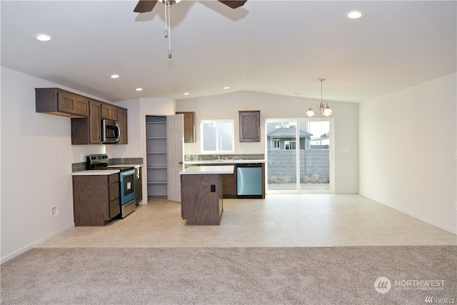 kitchen featuring light colored carpet, open floor plan, vaulted ceiling, appliances with stainless steel finishes, and a center island