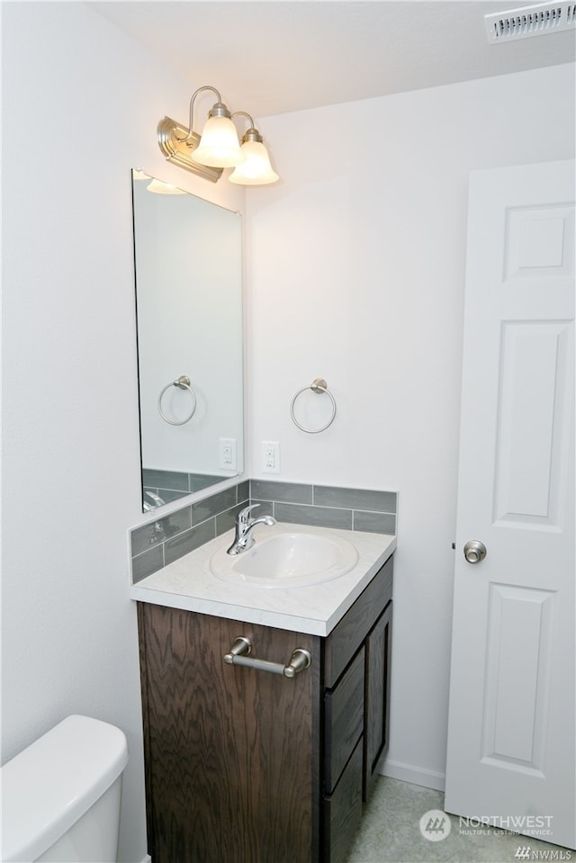 half bath with toilet, visible vents, and vanity