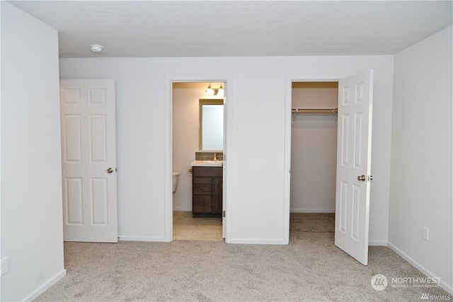 unfurnished bedroom with a closet, baseboards, a walk in closet, and carpet flooring