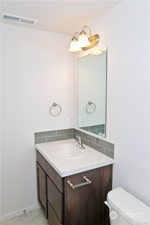 half bathroom with toilet, vanity, and visible vents