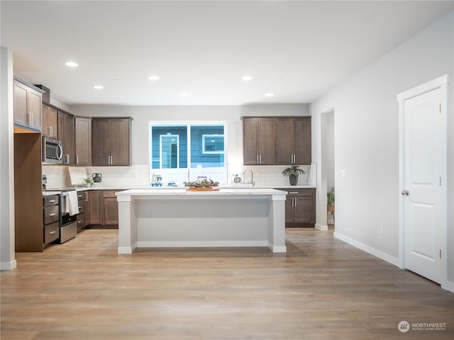 kitchen featuring light hardwood / wood-style floors, backsplash, stainless steel appliances, and a center island