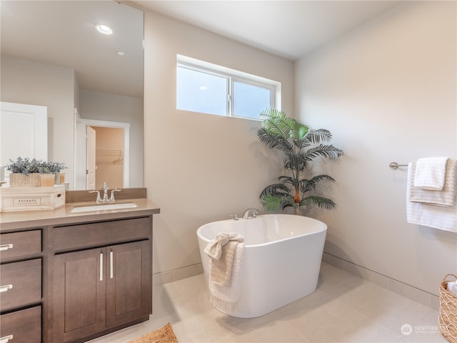 bathroom featuring a tub to relax in, vanity, and tile patterned floors