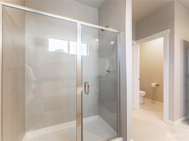 bathroom featuring tile patterned floors, toilet, and a shower with door