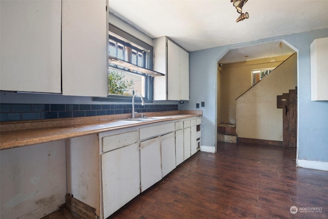 kitchen with white cabinets, sink, dark hardwood / wood-style flooring, and backsplash