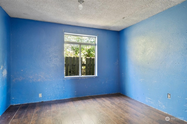 spare room with a textured ceiling and dark hardwood / wood-style floors