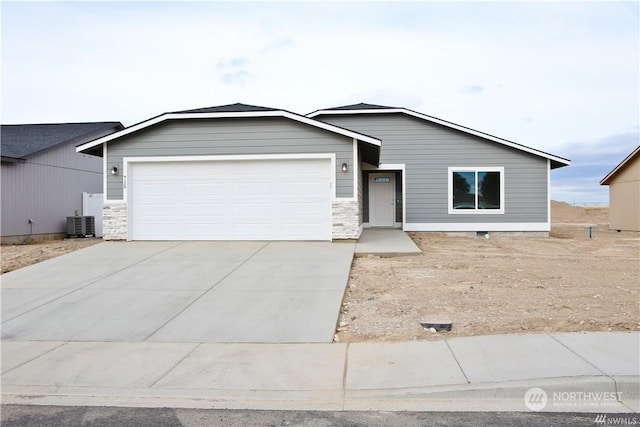 view of front of house with an attached garage, central air condition unit, and concrete driveway