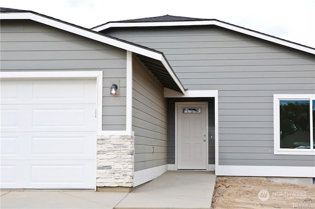 view of exterior entry featuring stone siding and an attached garage