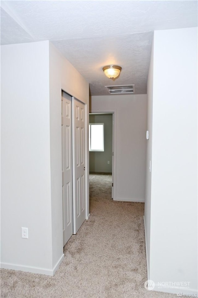 hallway featuring carpet, visible vents, and baseboards