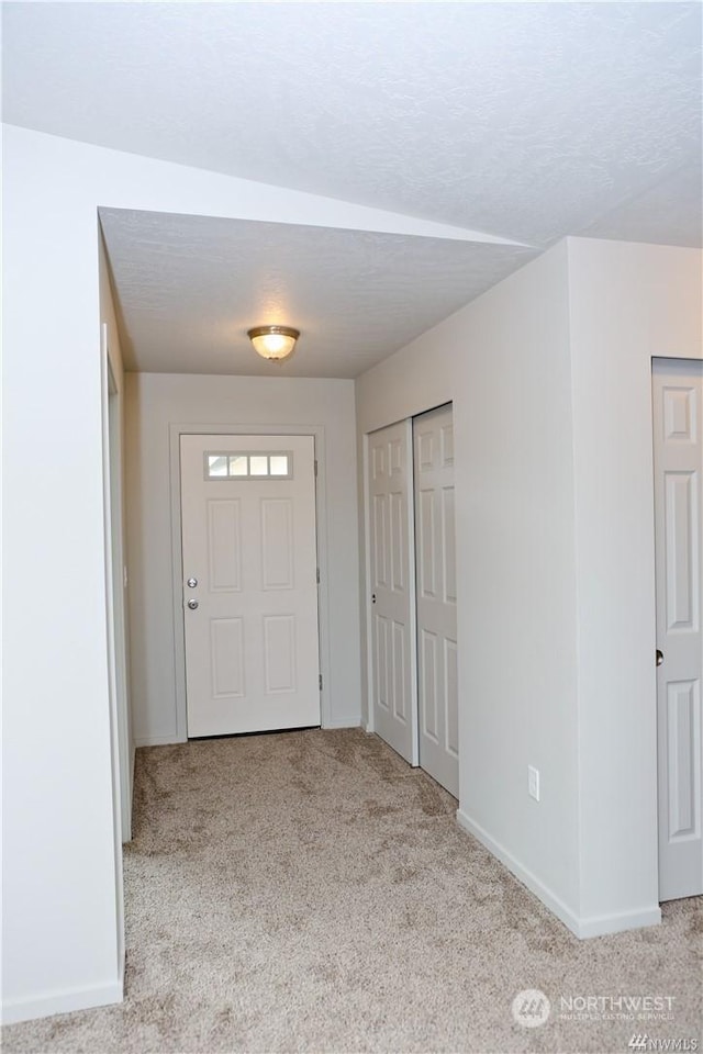 carpeted entrance foyer with baseboards and a textured ceiling