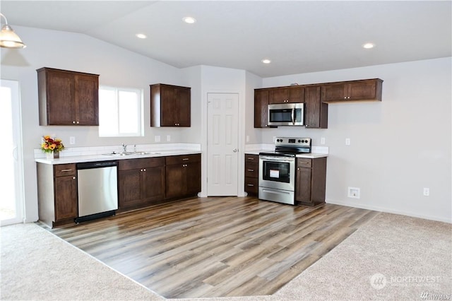 kitchen featuring stainless steel appliances, lofted ceiling, a sink, and dark brown cabinets