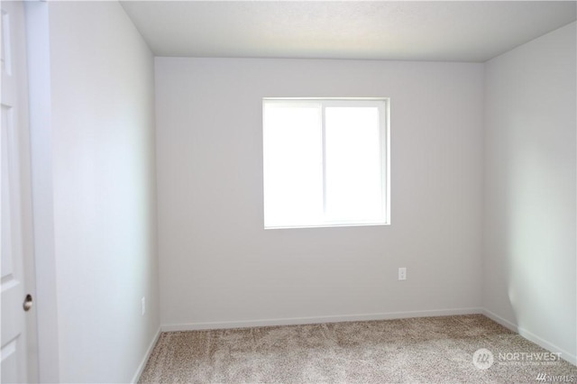 carpeted spare room featuring baseboards