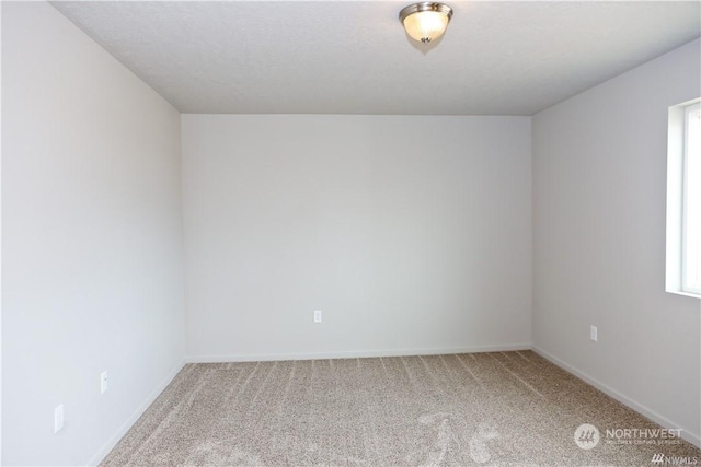 carpeted spare room featuring baseboards