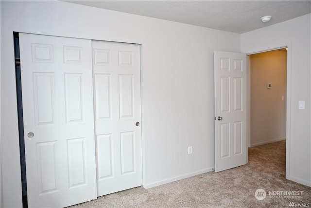 unfurnished bedroom with carpet, baseboards, and a closet