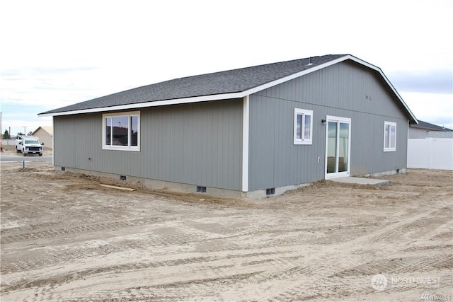 view of home's exterior featuring a shingled roof, crawl space, and fence