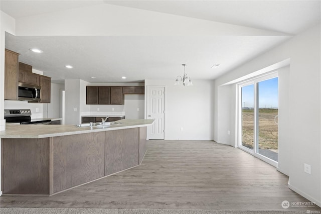 kitchen with light countertops, light wood-style flooring, an inviting chandelier, appliances with stainless steel finishes, and a sink