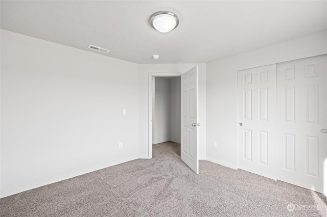 unfurnished bedroom with baseboards, a closet, visible vents, and carpet flooring