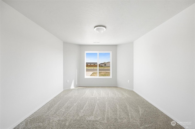 unfurnished room with carpet and baseboards