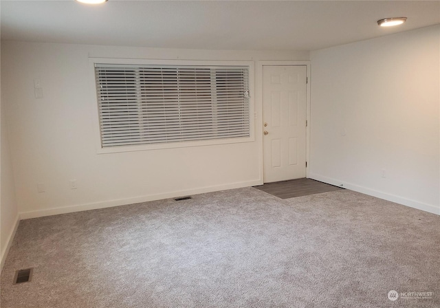 carpeted spare room featuring baseboards and visible vents