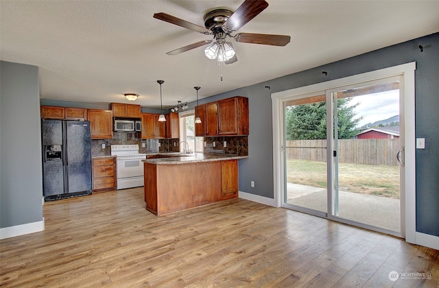 kitchen featuring black fridge with ice dispenser, white electric stove, kitchen peninsula, and plenty of natural light