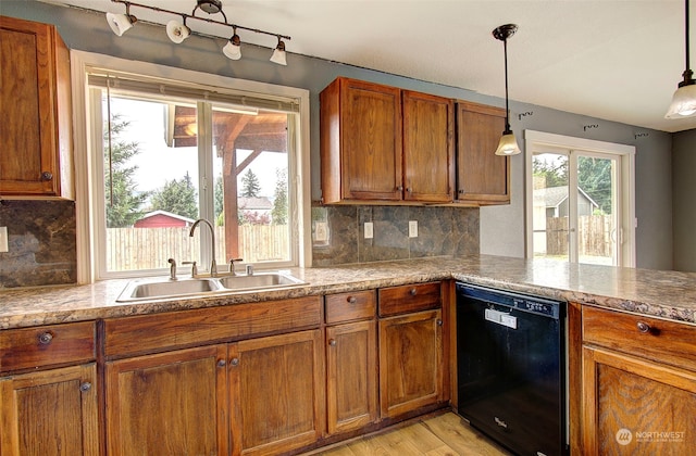 kitchen with black dishwasher, sink, hanging light fixtures, backsplash, and light hardwood / wood-style floors