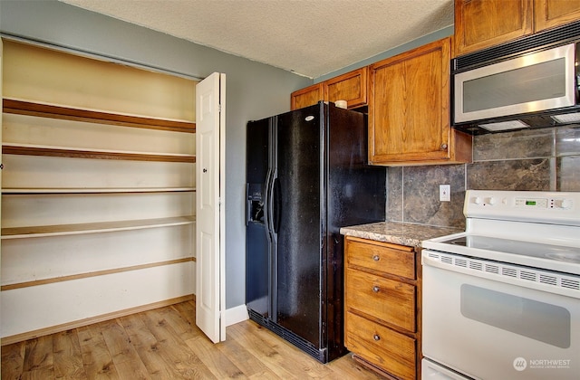 kitchen featuring electric stove, tasteful backsplash, black fridge with ice dispenser, light hardwood / wood-style floors, and a textured ceiling