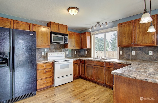 kitchen with tasteful backsplash, black fridge, sink, light hardwood / wood-style flooring, and white electric stove