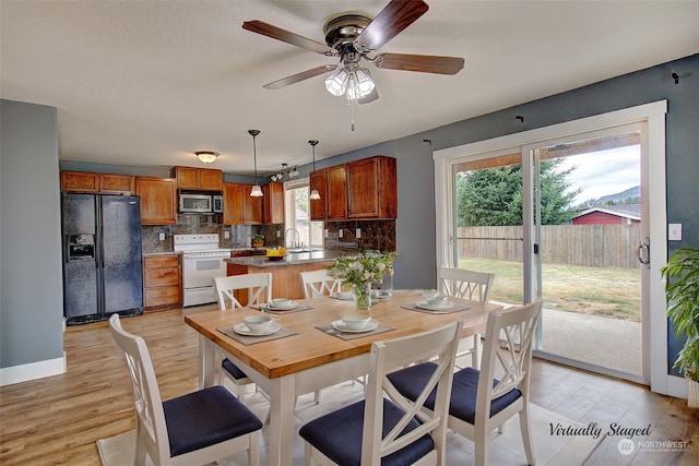 dining space featuring light hardwood / wood-style flooring, sink, a wealth of natural light, and ceiling fan