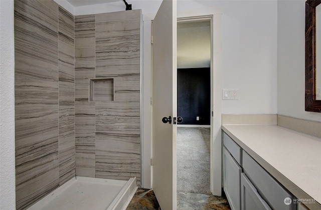 bathroom featuring vanity, tile patterned flooring, and a tile shower