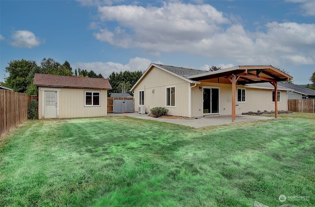 back of house with an outbuilding, a patio area, and a yard