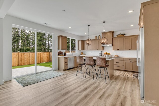 kitchen with stainless steel dishwasher, a kitchen bar, a center island, and light hardwood / wood-style floors