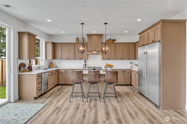 kitchen featuring a wealth of natural light, stainless steel appliances, a center island, and a kitchen bar