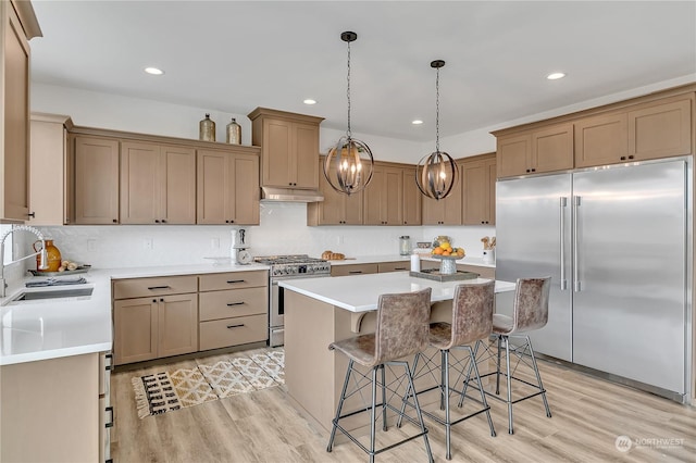 kitchen featuring a kitchen island, appliances with stainless steel finishes, light countertops, light wood-type flooring, and a kitchen bar