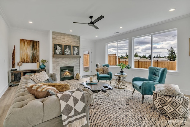 living area with recessed lighting, a tile fireplace, crown molding, and wood finished floors