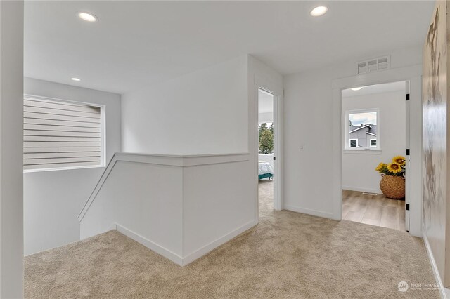 corridor with carpet floors, an upstairs landing, visible vents, and recessed lighting