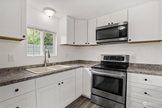 kitchen with stainless steel appliances, sink, white cabinets, and dark hardwood / wood-style floors