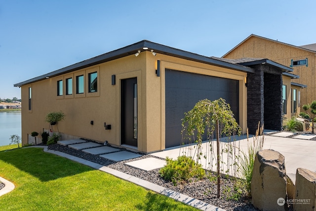 view of front of home with a garage, a front lawn, and a water view