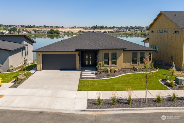 view of front facade with a garage, a water view, and a front lawn