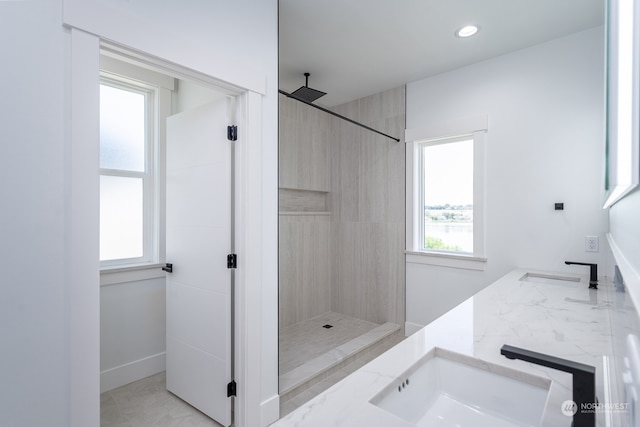 bathroom with a tile shower and vanity