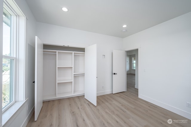 unfurnished bedroom with light wood-type flooring and a closet