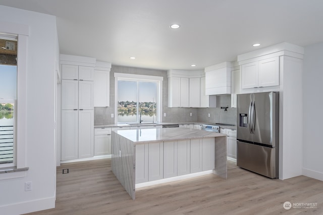 kitchen featuring backsplash, white cabinets, a center island, light hardwood / wood-style floors, and stainless steel appliances