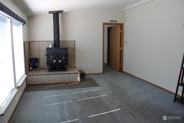 unfurnished living room with a wood stove and carpet