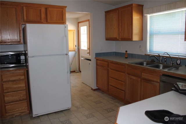 kitchen featuring sink, white fridge, dishwashing machine, and light tile patterned floors