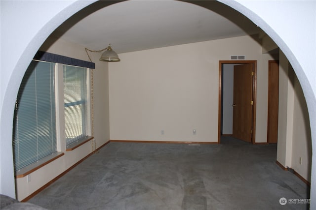 carpeted empty room featuring vaulted ceiling