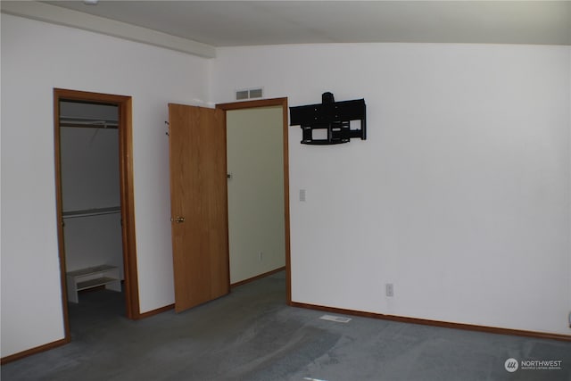 unfurnished bedroom featuring carpet flooring, lofted ceiling, a closet, and a spacious closet