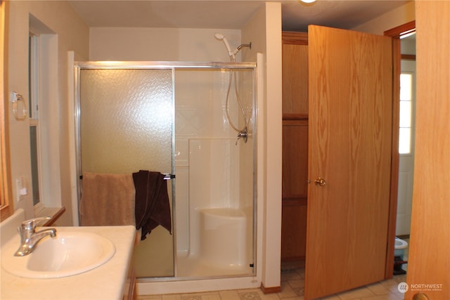 bathroom featuring a shower with shower door, vanity, and tile patterned flooring