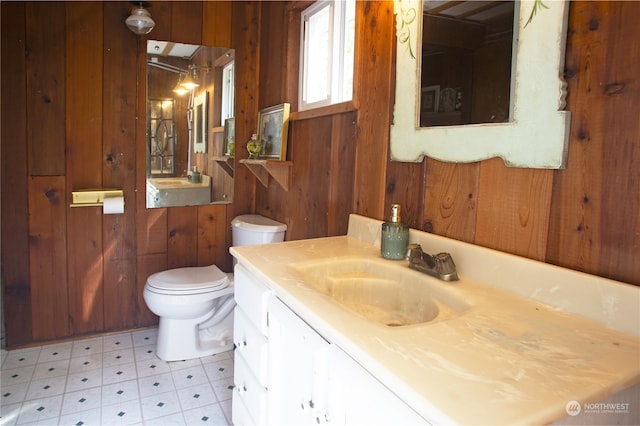 bathroom featuring vanity, tile patterned flooring, wooden walls, and toilet