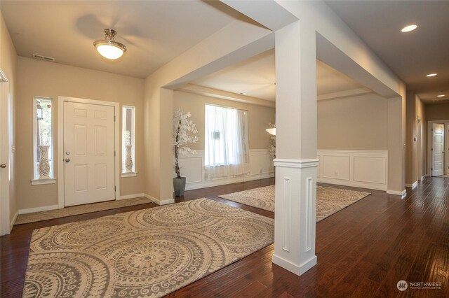 foyer with decorative columns, a wealth of natural light, and dark wood-type flooring