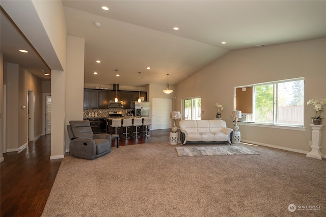 living room with a healthy amount of sunlight, dark hardwood / wood-style flooring, and high vaulted ceiling