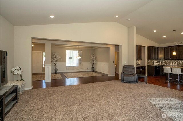 carpeted living room with high vaulted ceiling